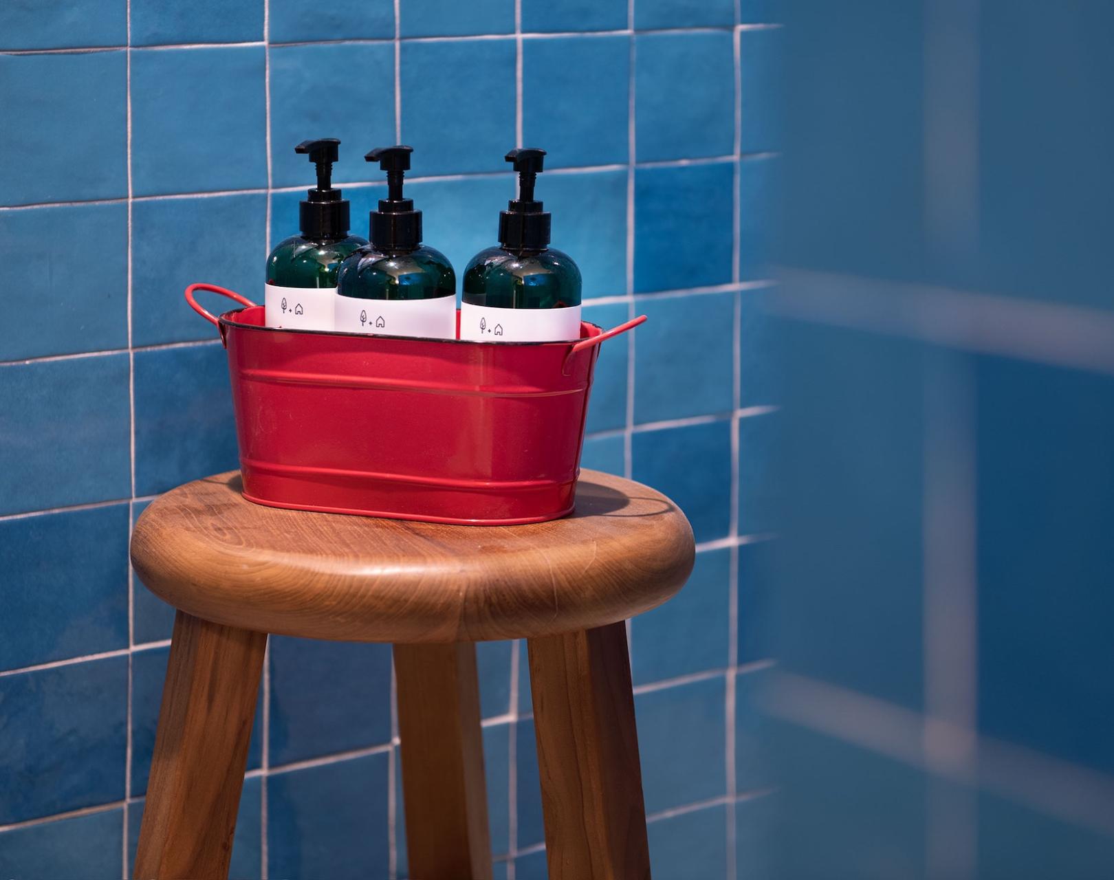 Wooden bench with a red bucket of bottles in a shower