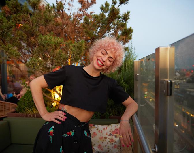 A woman with pink hair smiling at The Nest rooftop