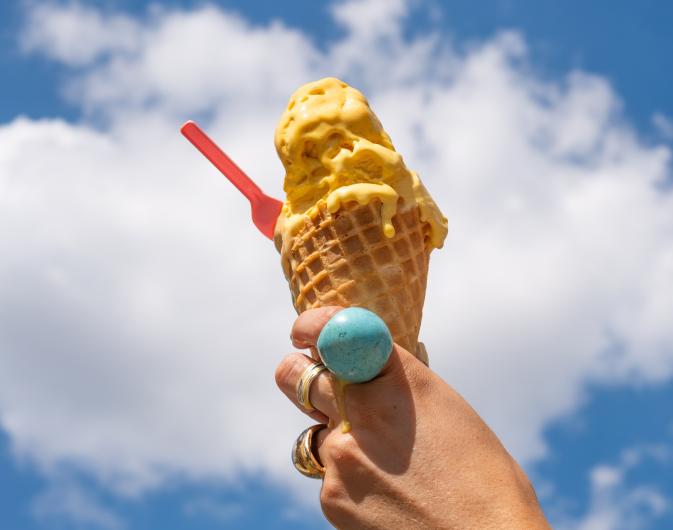 Someone with rings holding an ice cream cone towards the sky