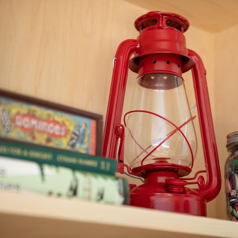 Red lantern next to a jar of buttons and some books