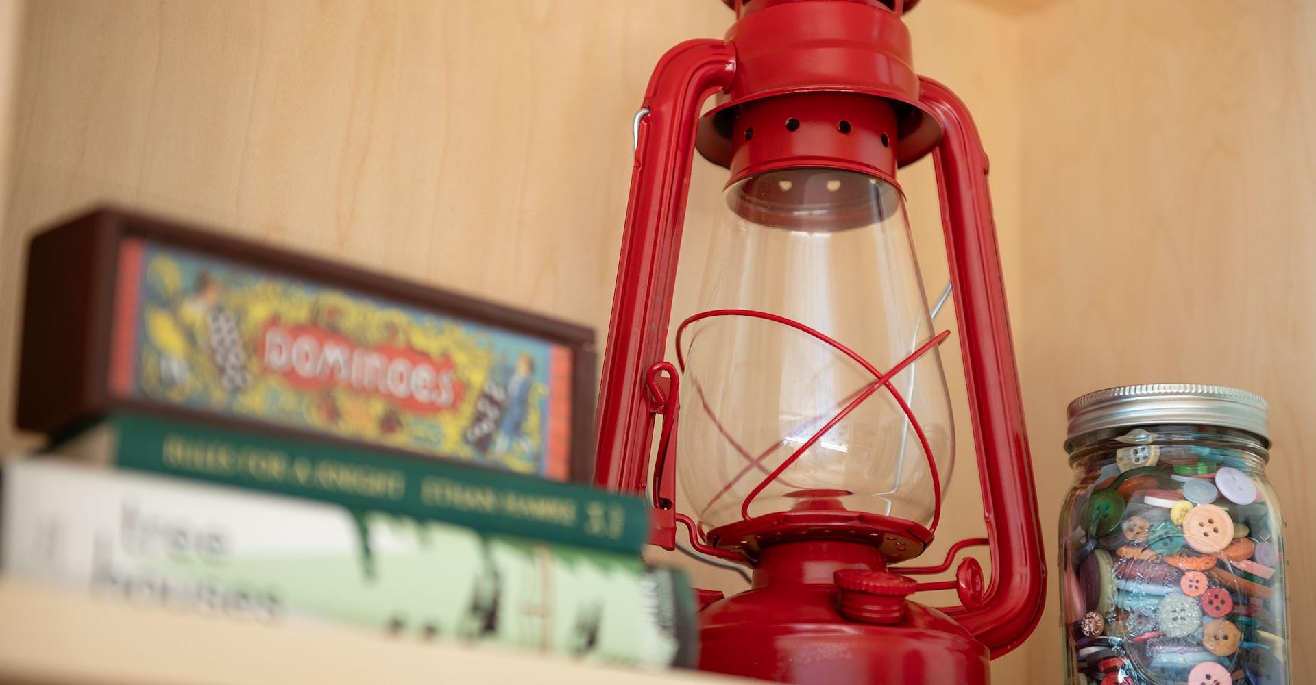 Red lantern next to a jar of buttons and some books