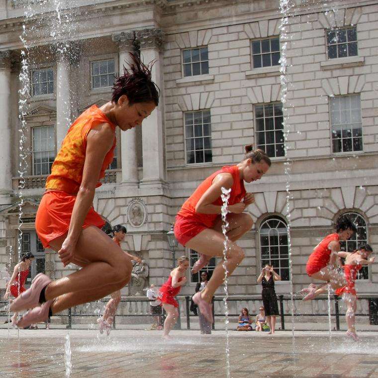 women in orange outfits dancing in water at Somerset House