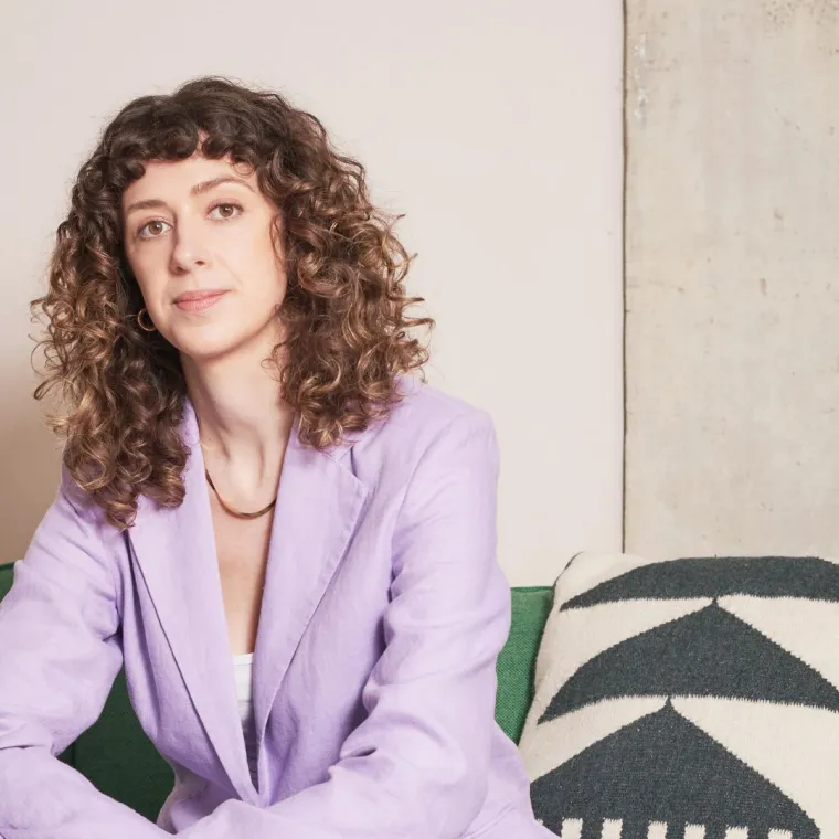 A woman in a purple blazer sitting on a green couch