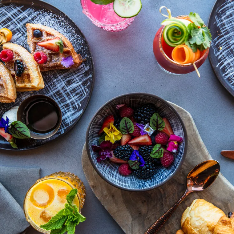 tablescape of breakfast foods including waffles and fruit salad