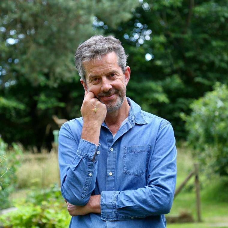 Alex Monroe standing and smiling in a garden