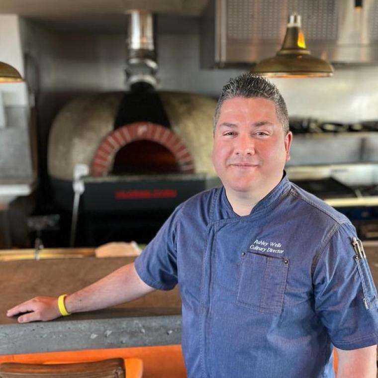 Ashley Wells in a chef coat standing in a kitchen