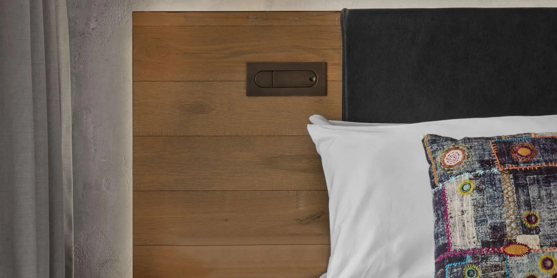 Bed with a colourful pillow and bedside table with a red drawer